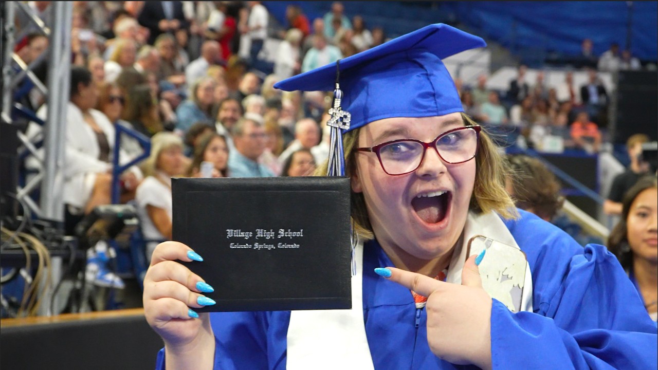 A Village High School student points at her diploma during the graduation ceremony.